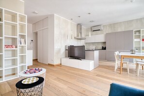 Eine moderne Küche mit integriertem Fernseher, weißen Schränken und einem Essbereich mit Tisch und Stühlen.
