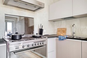 Une cuisine moderne dotée d’appareils électroménagers en acier inoxydable, d’un four encastré et d’une grande fenêtre qui laisse entrer la lumière naturelle.