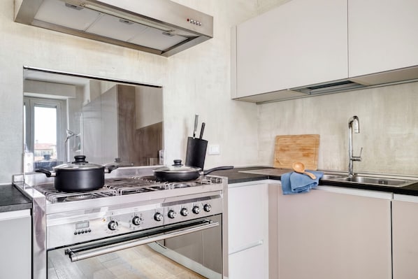 Eine moderne Küche mit Edelstahlgeräten, einem eingebauten Ofen und einem großen Fenster, das für natürliches Licht sorgt.