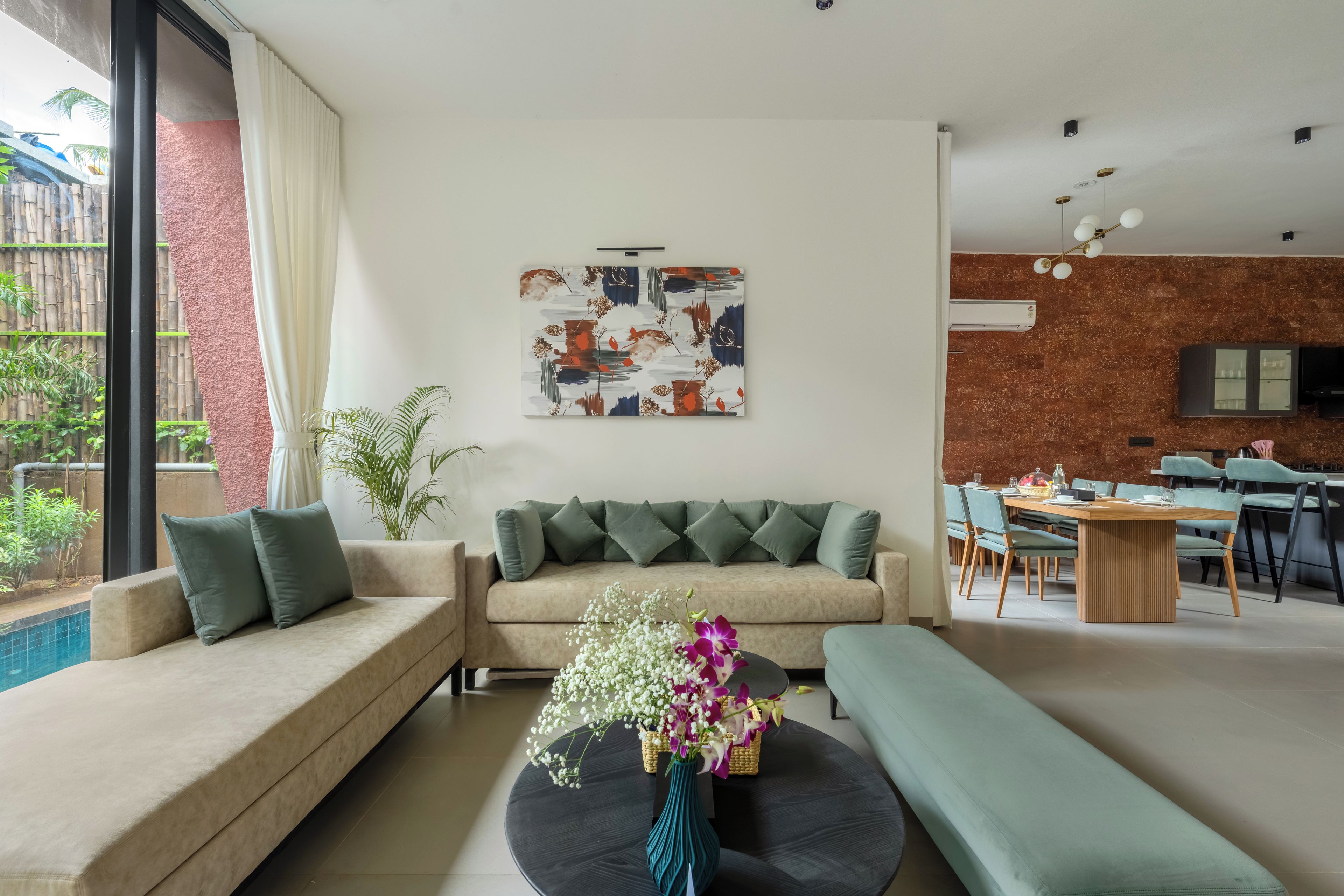 A modern living room with a sofa, a dining area, and a view of the outdoors.