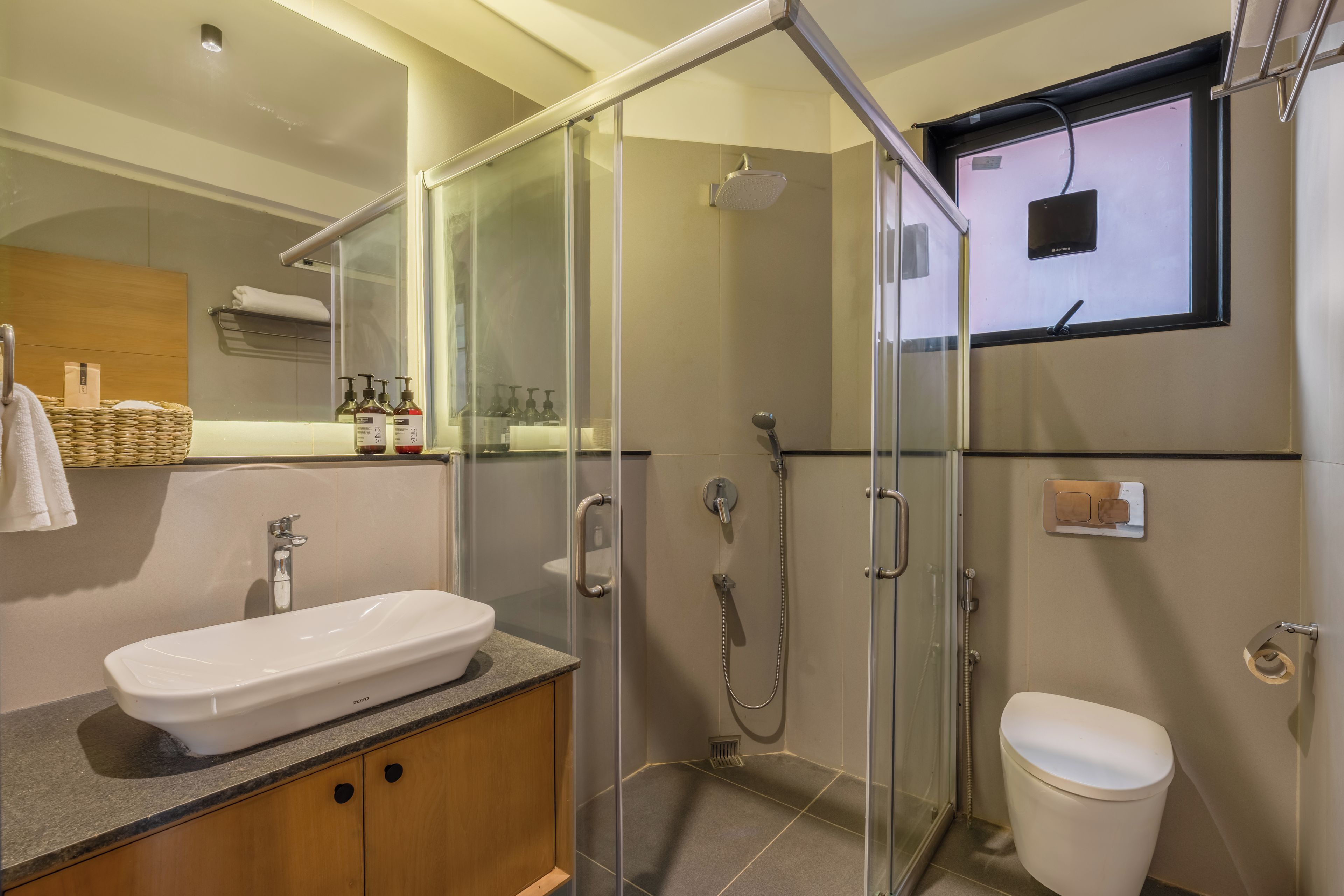 A modern bathroom with a glass-enclosed shower, a white sink, and a toilet.
