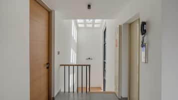 Een gang met een houten deur, een trap en een telefoon aan de muur.