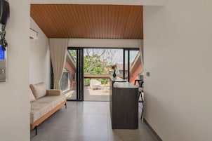 Un interior moderno con un sofá, una mesita y vista a un jardín a través de un ventanal.