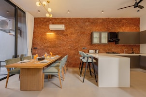 Una cocina moderna con una isla central, un comedor con una mesa larga y sillas, y un horno empotrado.
