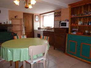 A kitchen with a dining table, chairs, a microwave, and a cabinet with glassware.