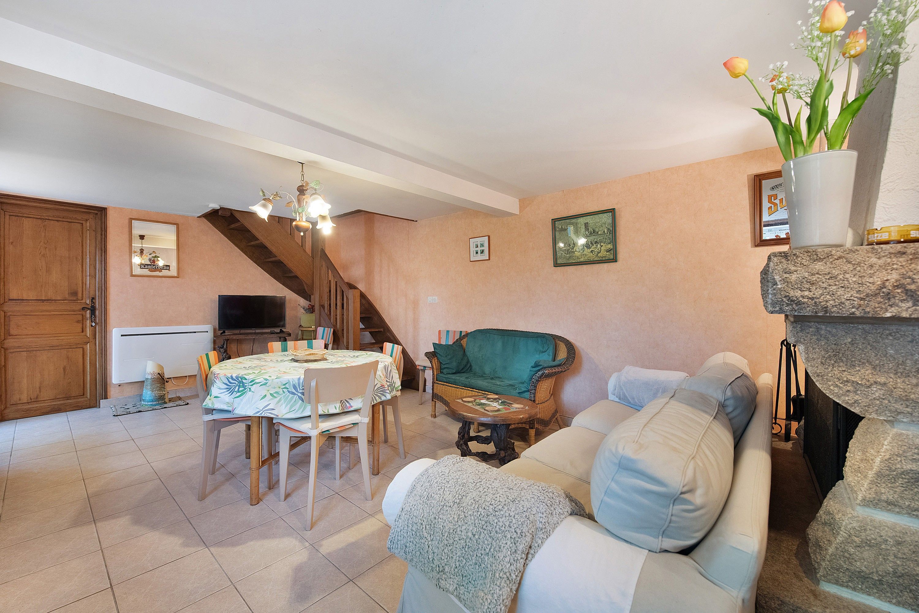 Una sala de estar acogedora con comedor, un sillón verde, un sofá y una chimenea.