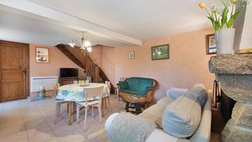 Una sala de estar acogedora con comedor, un sillón verde, un sofá y una chimenea.