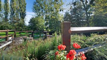 A garden with a wooden fence, a stone wall, and a variety of plants and flowers.