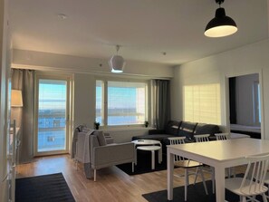A modern living room with a sofa, a dining table, and a large window.