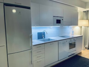 Una cocina moderna con microondas integrado, horno y pileta doble.