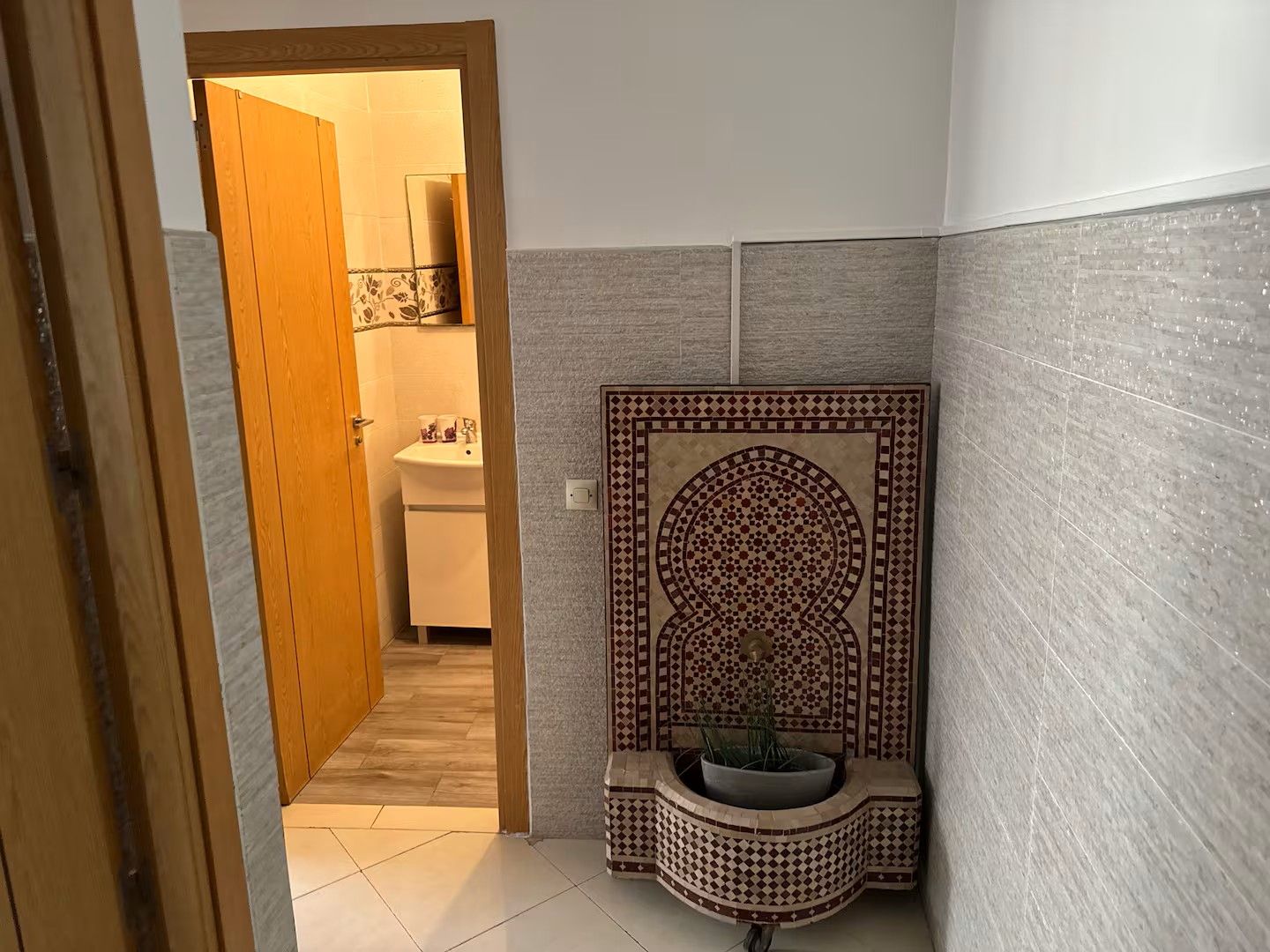 Un baño con piso de cerámica, un lavamanos y un panel decorativo en la pared.