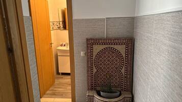 Un baño con piso de cerámica, un lavamanos y un panel decorativo en la pared.