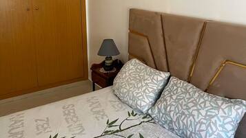 A bedroom with a bed, a nightstand, a lamp, and a wardrobe.