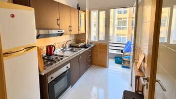 A compact kitchen with a refrigerator, stove, and cabinets.