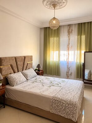 Quarto com cama grande, mesa de cabeceira, abajur e luminária pendente.