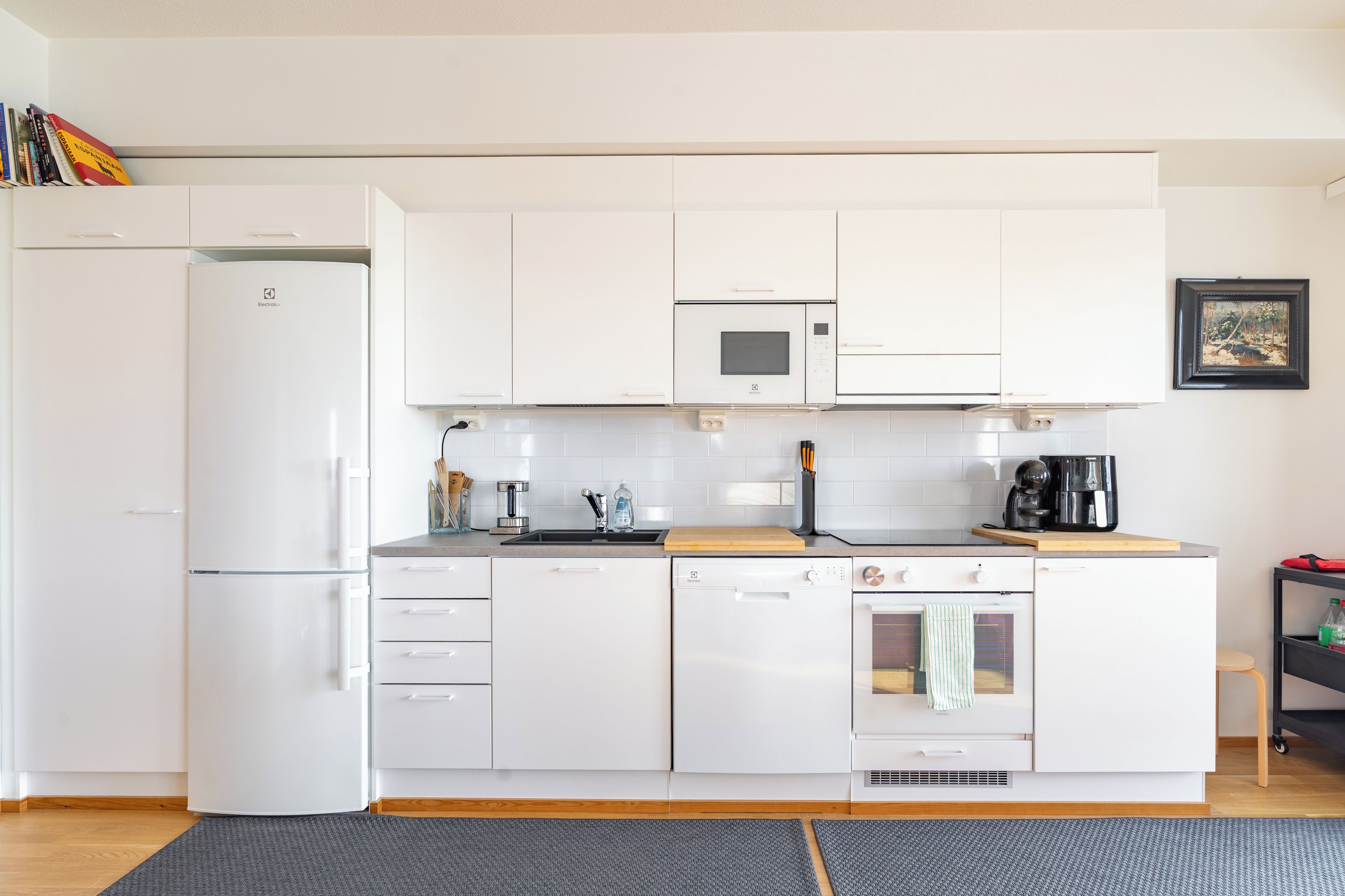Una cocina moderna con gabinetes blancos, microondas integrado, lavavajillas y horno.