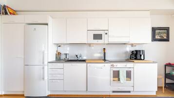 Una cocina moderna con gabinetes blancos, microondas integrado, lavavajillas y horno.