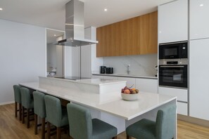 A modern kitchen with a central island, stainless steel appliances, and wooden cabinetry. - Premium 4-bed villa, superb seaview|Serenity Ocean (Estreito da Calheta)