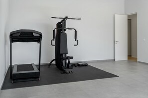 Et hjemmegym med løbebånd, vægtbænk og træningsmaskine.