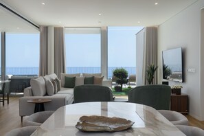 A modern living room with a sofa set, a dining area, and a balcony with a view. - Premium 4-bed villa, superb seaview|Serenity Ocean (Estreito da Calheta)
