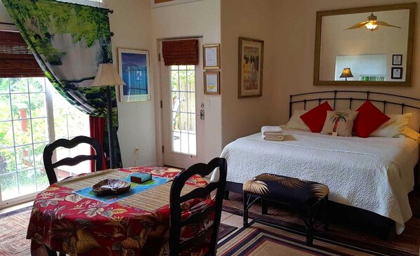 Un dormitorio con cama, una mesa, sillas, una ventana con cortinas y una puerta.