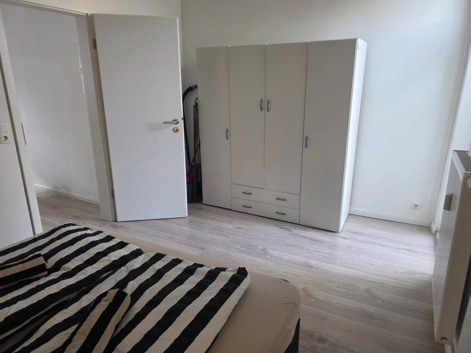 A bedroom with a bed, a wardrobe, and a door.