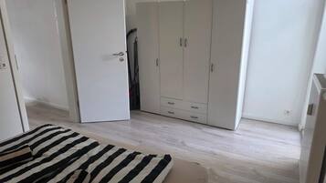 A bedroom with a bed, a wardrobe, and a door.
