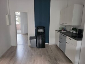 A modern kitchen with white cabinets, a black refrigerator, and a coffee machine. - Cozy apartment in the KTV with a terrace (Rostock)