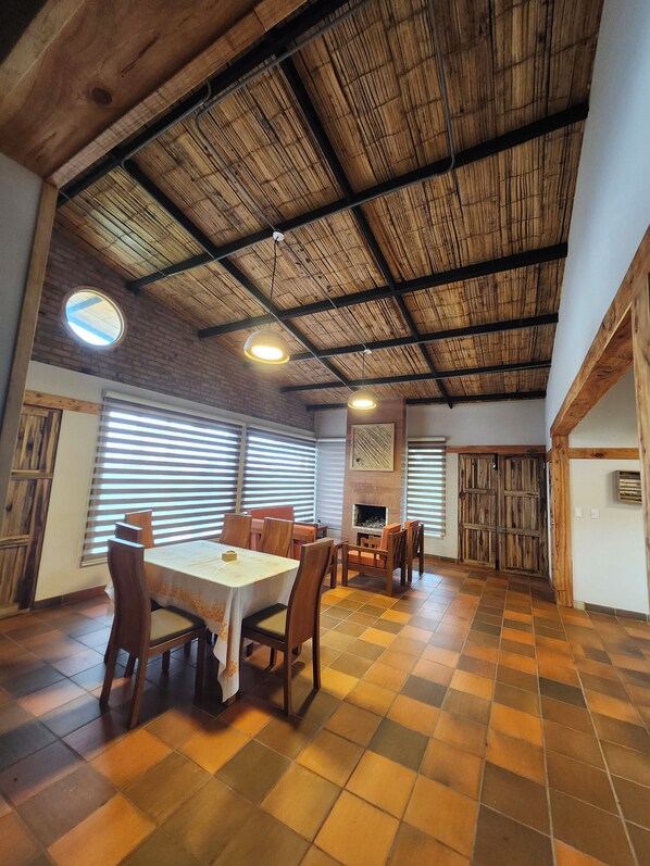 A spacious dining area with a high ceiling, wooden beams, and a checkered floor.