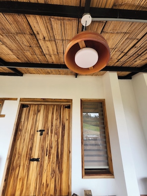 A room with a wooden ceiling, a large wooden door, and a window with blinds.