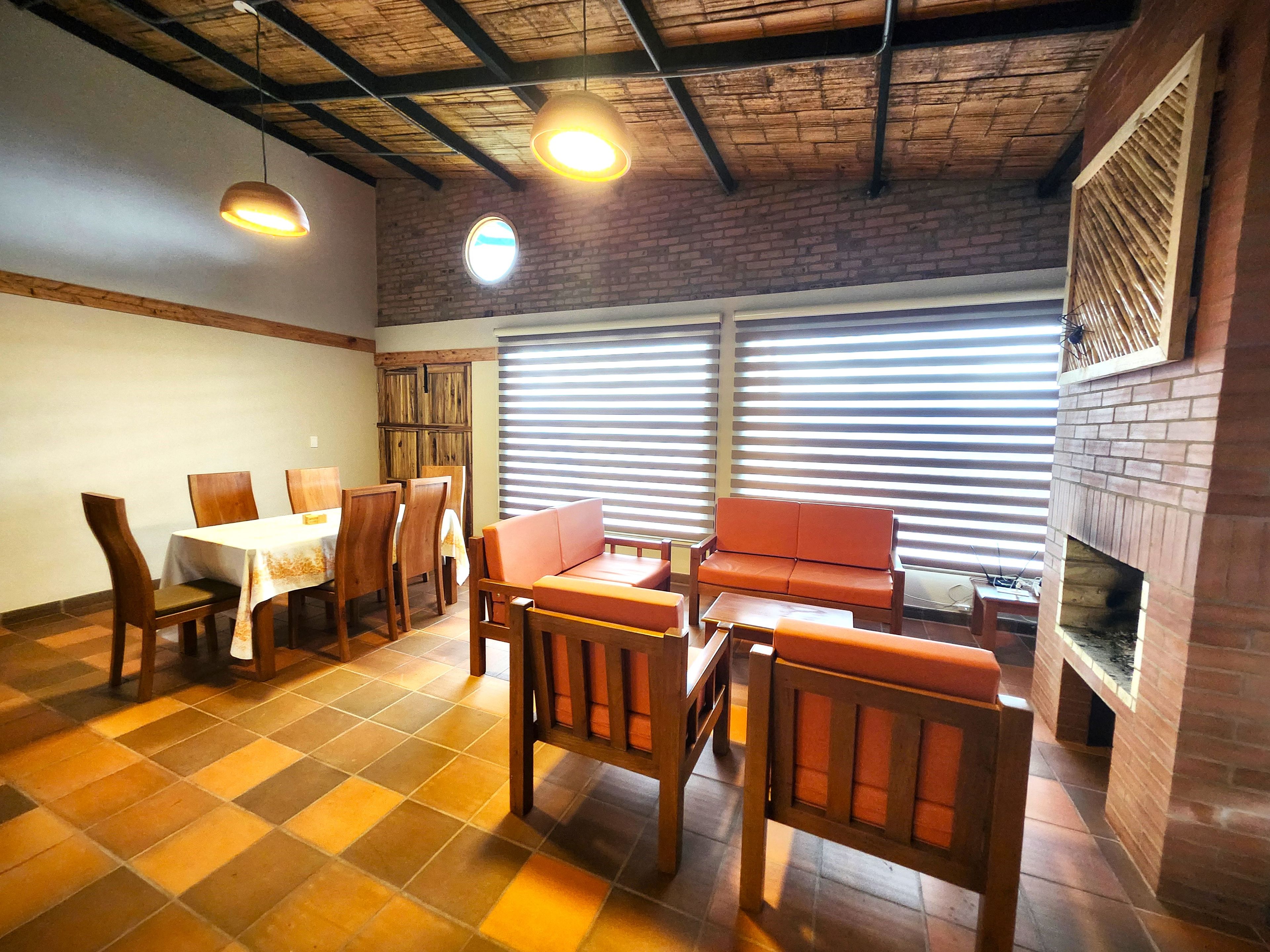 A dining area with a brick fireplace, wooden furniture, and a checkered floor.