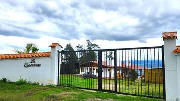 A gated property with a sign reading 'La Esperanza,' a building with a red roof, and a grassy area in front.