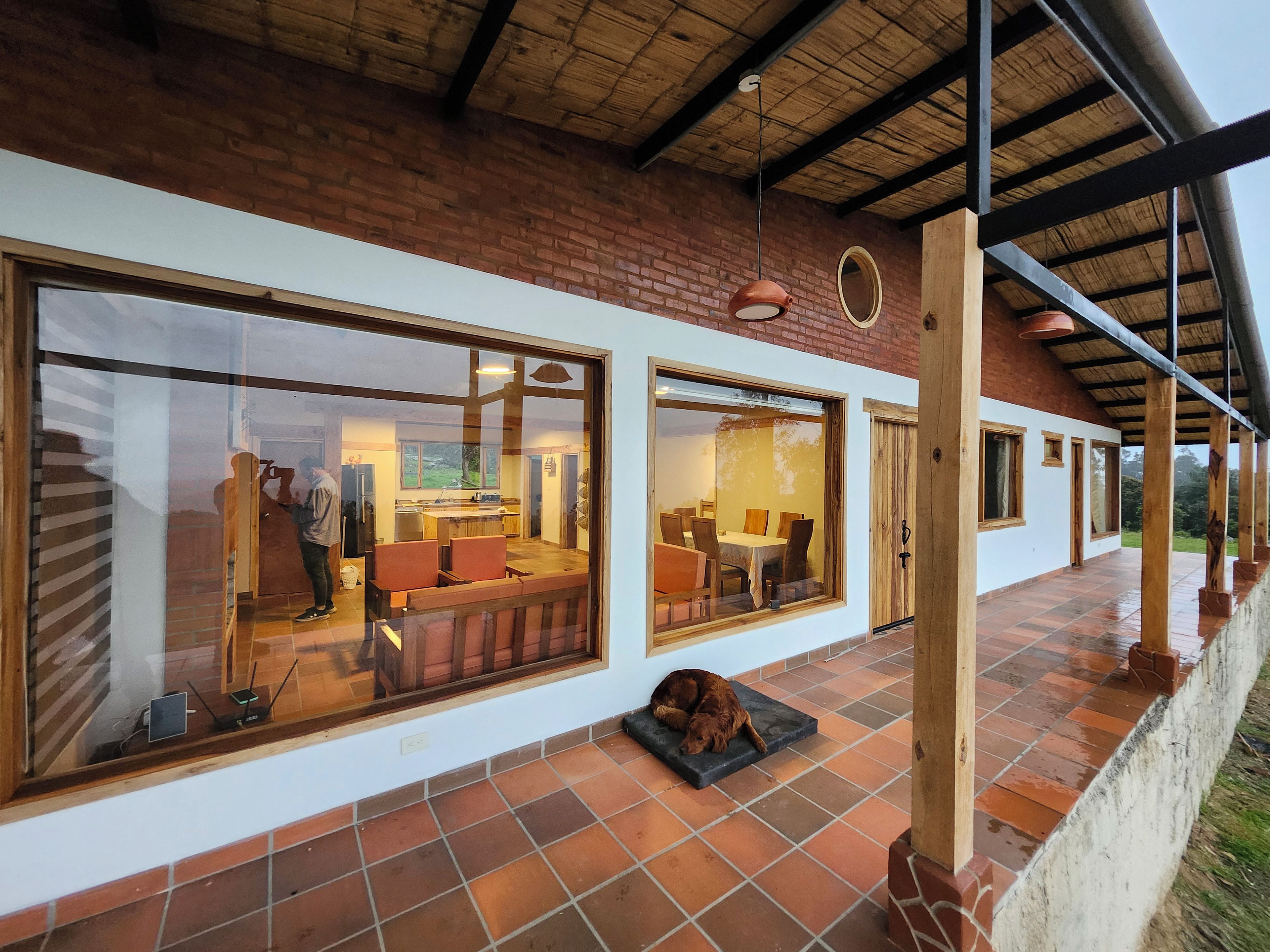 A modern house with large windows, a patio, and a dog resting on a mat.