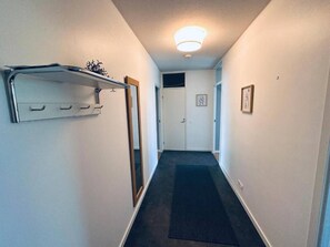 A narrow hallway with a coat rack, a door at the end, and a light fixture on the ceiling. - Spacious 1BR Near Metro and Major Shopping Center (Espoo)