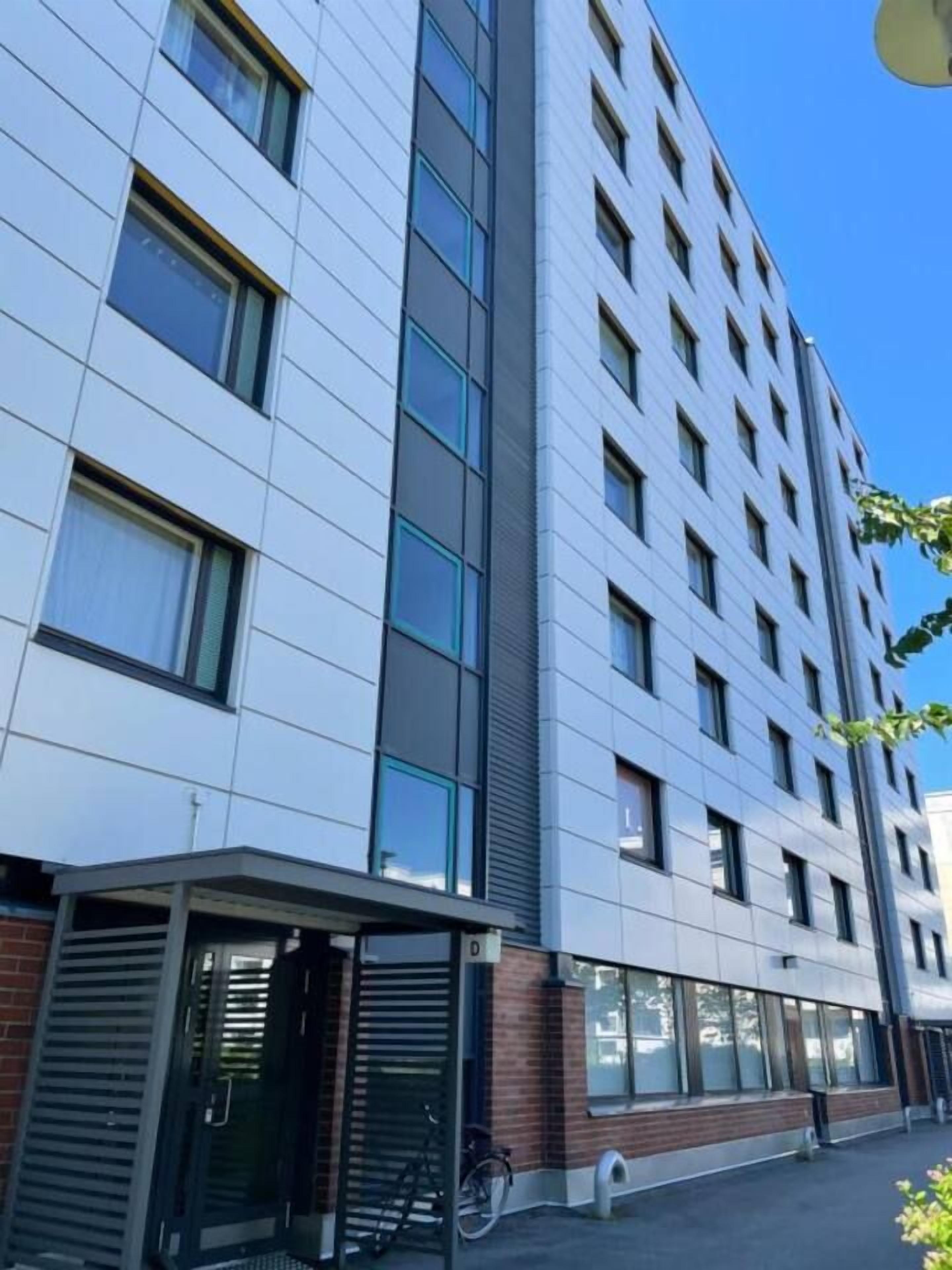 A multi-story building with a modern architectural design, featuring a combination of glass and brick facade, and a covered entrance area.