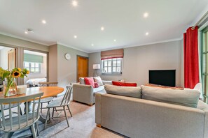 Una sala de estar moderna con un sofá, un televisor y un comedor con mesa y sillas.