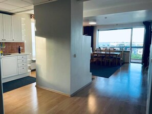 A modern interior with a kitchen, dining area, and a view through a large window.