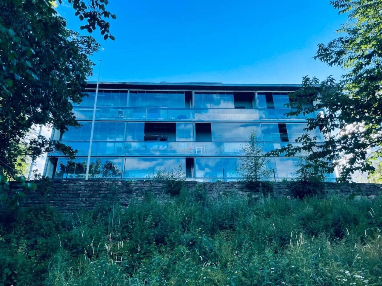 Un edificio de varios pisos con un diseño arquitectónico moderno, que destaca por sus amplios ventanales y techo plano.