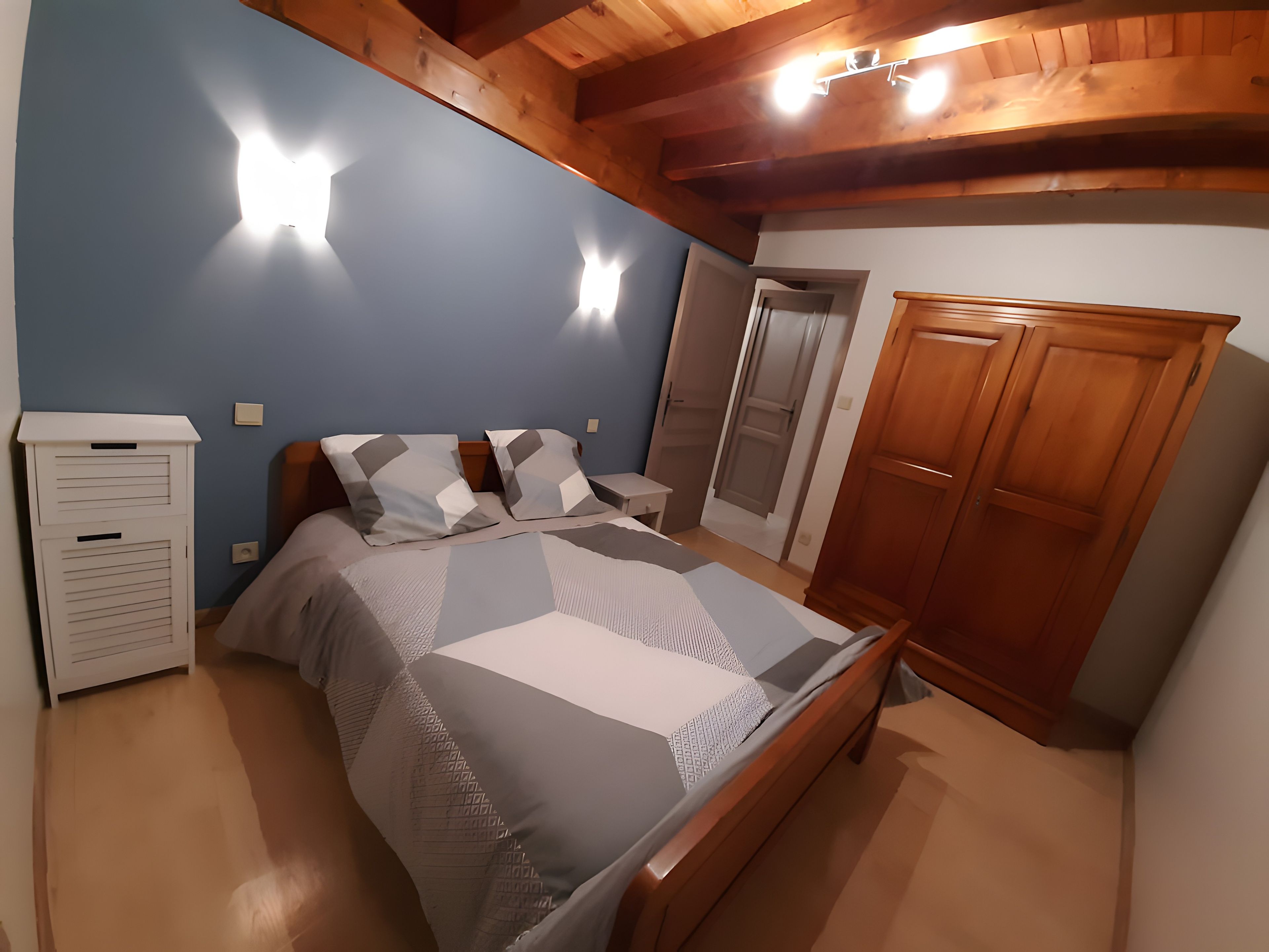Une chambre à coucher avec un lit, une armoire en bois et un meuble blanc.