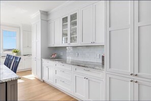 Een keuken met witte kasten, een marmeren aanrechtblad en een raam dat voor natuurlijk licht zorgt.