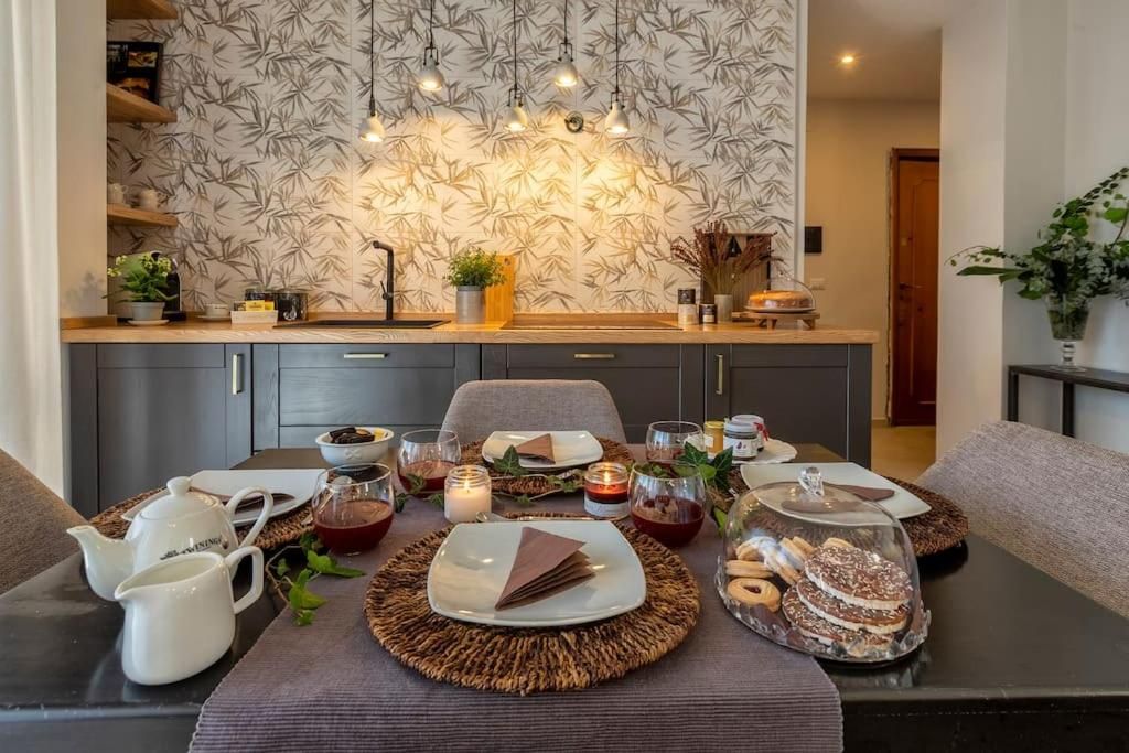 A dining area with a table set for a meal, featuring a placemat, plates, cutlery, and a glass container with pastries.