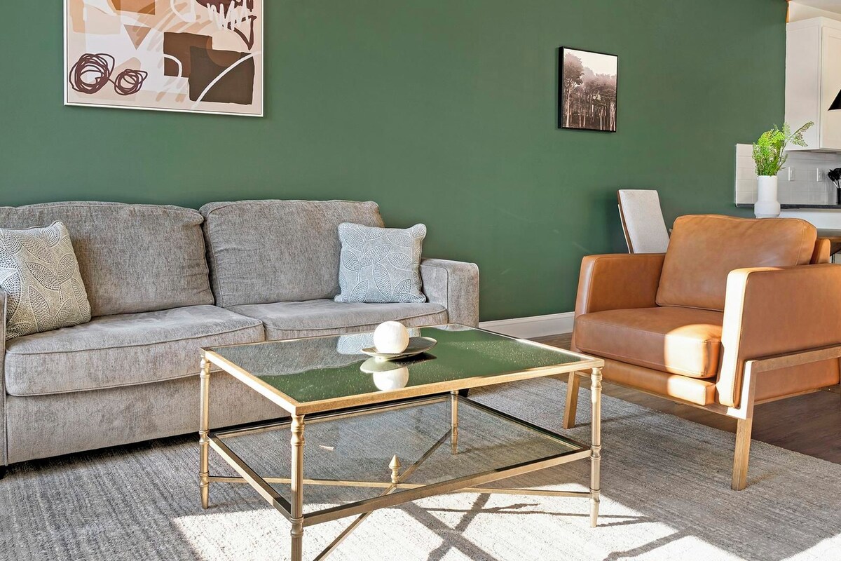 A living room with a grey sofa, a brown leather armchair, and a green coffee table.