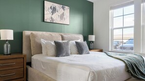 A bedroom with a bed, two bedside tables, a window, and a wall-mounted artwork. - Landing Amazing 1bd, Gym, Game Room (Gainesville)