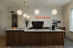 Una cocina con isla central, máquina de café y lámparas colgantes.