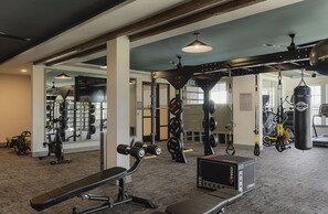 Un gimnasio con equipamiento de levantamiento de pesas, máquinas de cardio y un saco de boxeo.
