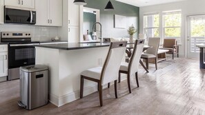 Una cocina moderna con una isla central, electrodomésticos de acero inoxidable y una zona de comedor con sillas y una mesa.