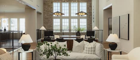 A spacious living room with a stone wall, large windows, and a high ceiling.