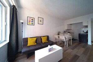 A modern living room with a sofa, a coffee table, and a dining area with chairs and a table. - Cute Studio in DT Montreal, 5 mins to bell center (Montreal)