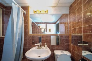 A bathroom with a sink, toilet, and a shower curtain. - Cute Studio in DT Montreal, 5 mins to bell center (Montreal)