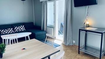 Un soggiorno moderno con un divano, un tavolo da pranzo e una TV a parete.